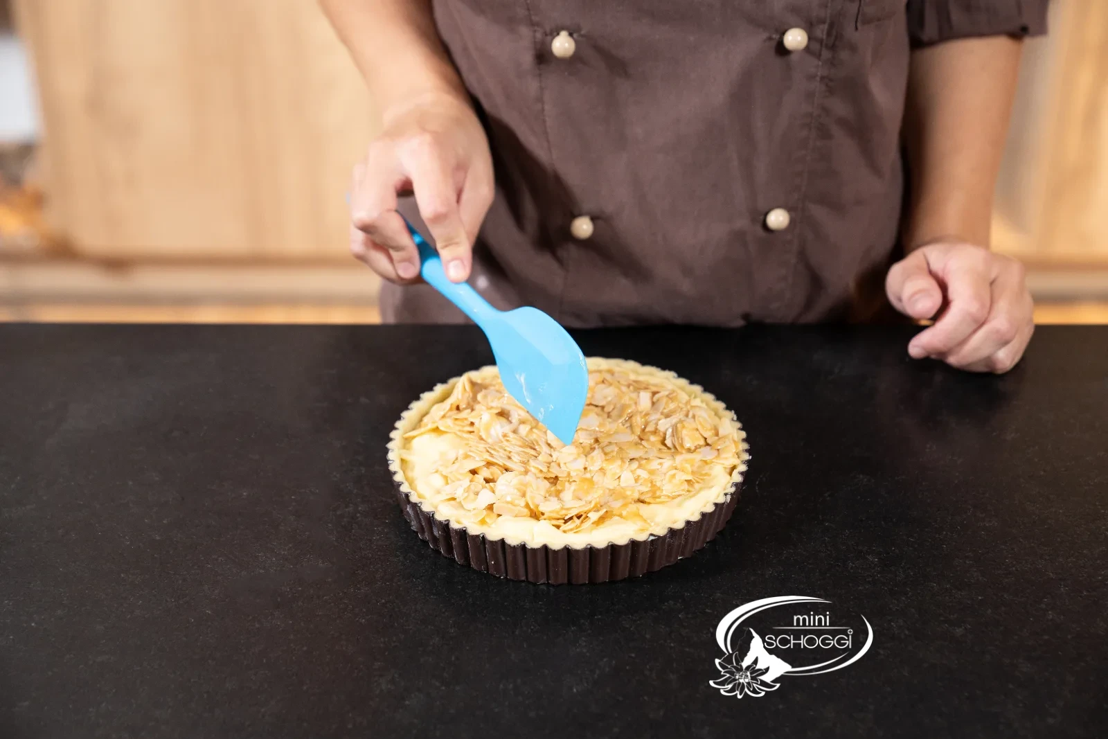 La massa calda di mandorle e caramello viene distribuita sulla crostata con un raschietto per impasto