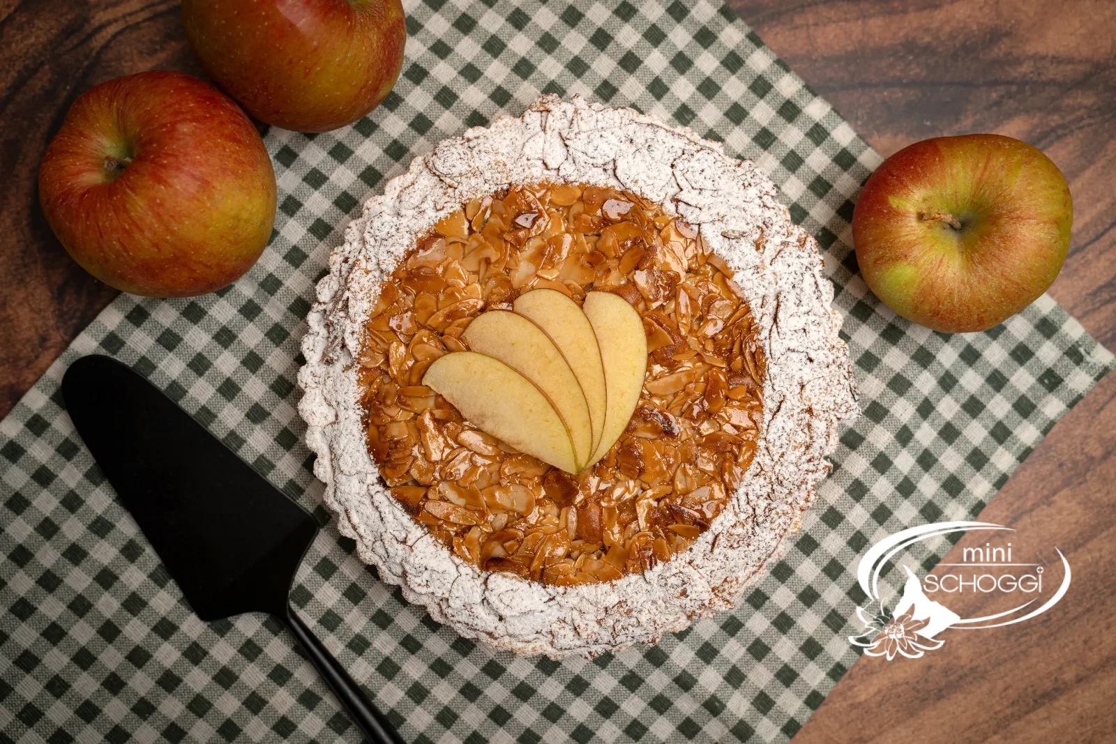 Crostata di mele con copertura dorata di mandorle affettate, il bordo spolverato di zucchero a velo