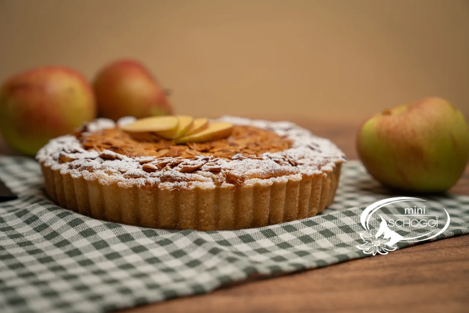 Crostata di mele con copertura dorata di mandorle in scaglie, il bordo spolverato con zucchero a velo