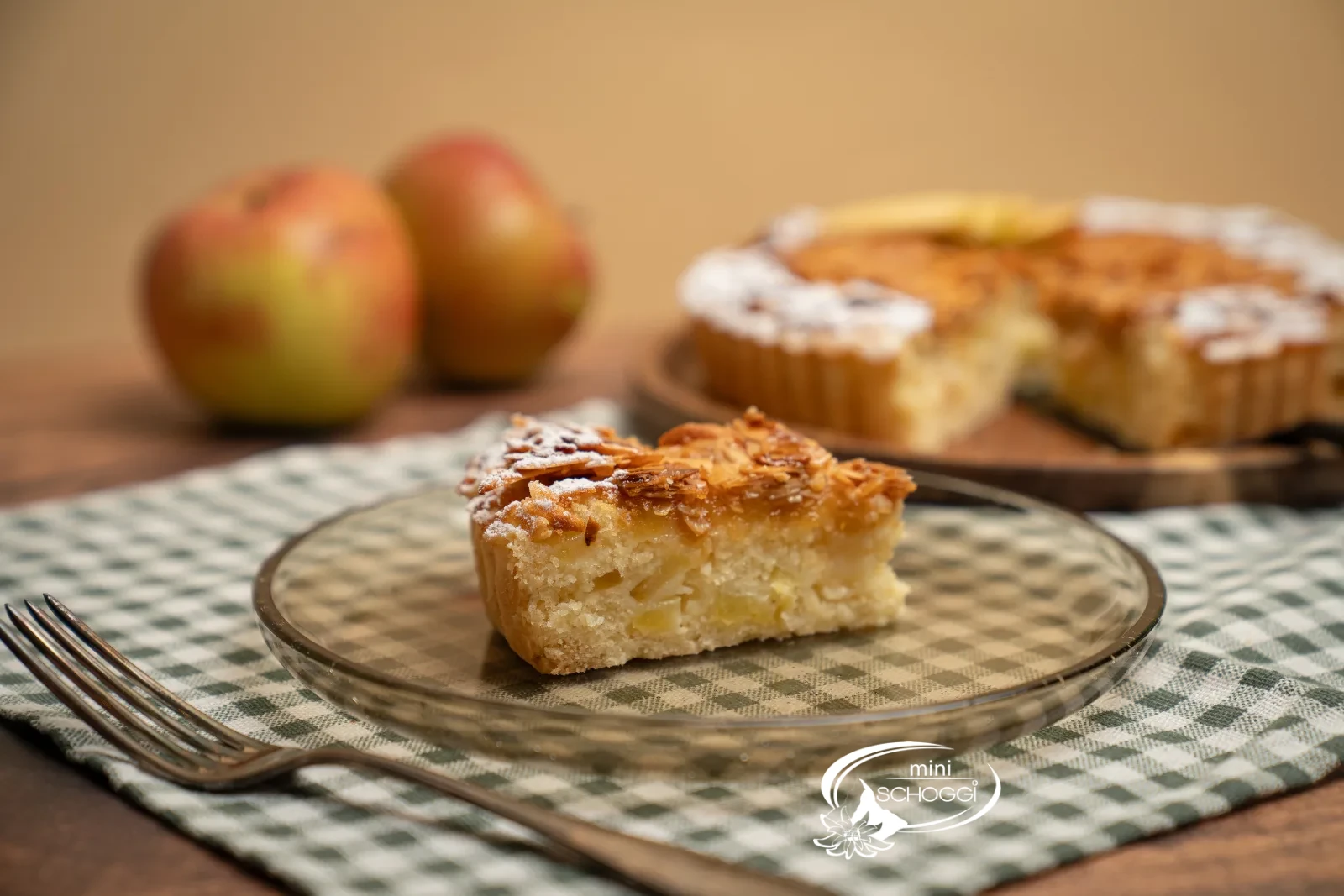 Crostata di mele con copertura dorata di mandorle affettate, il bordo spolverato di zucchero a velo