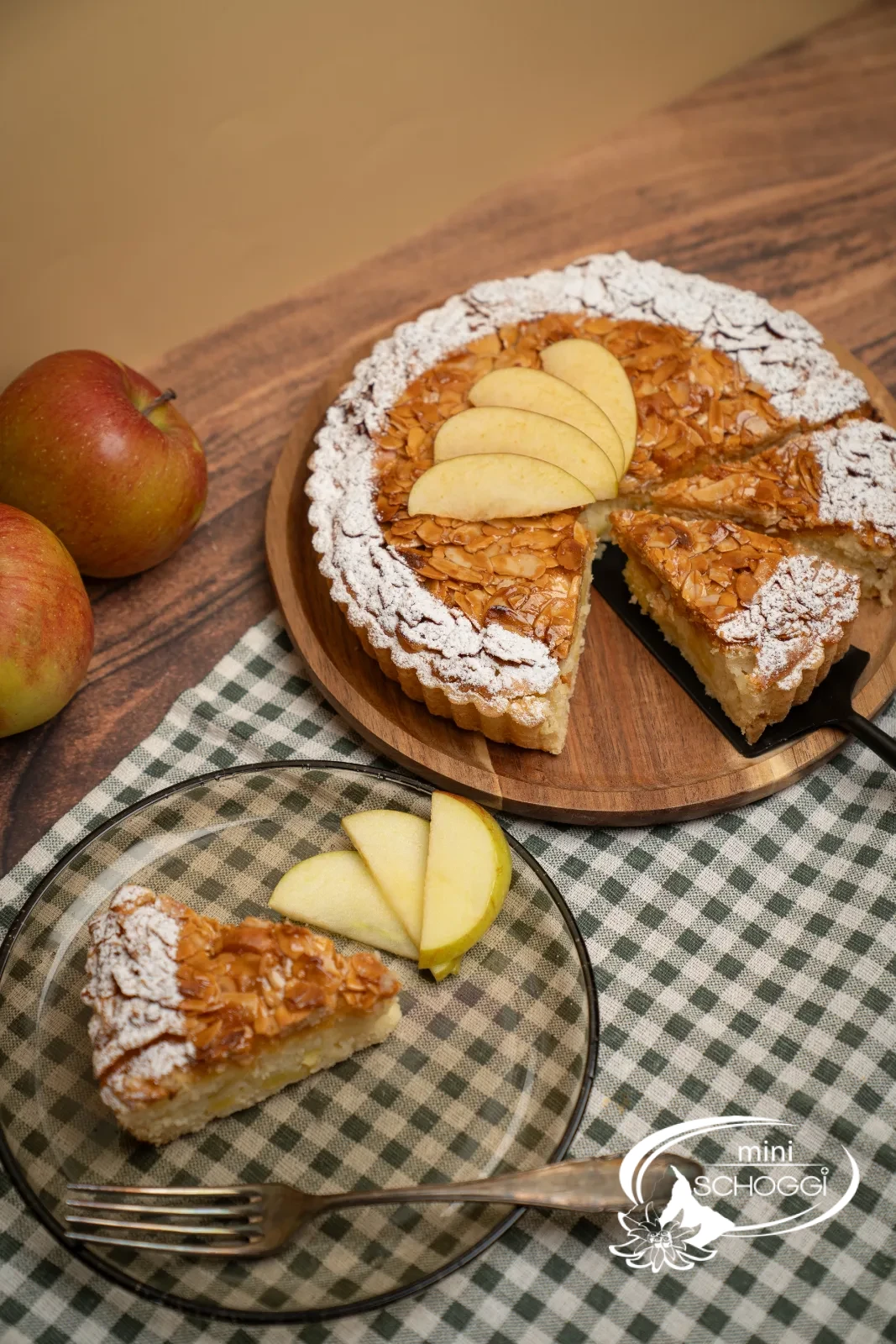 Crostata di mele con copertura dorata di mandorle affettate, il bordo spolverato di zucchero a velo
