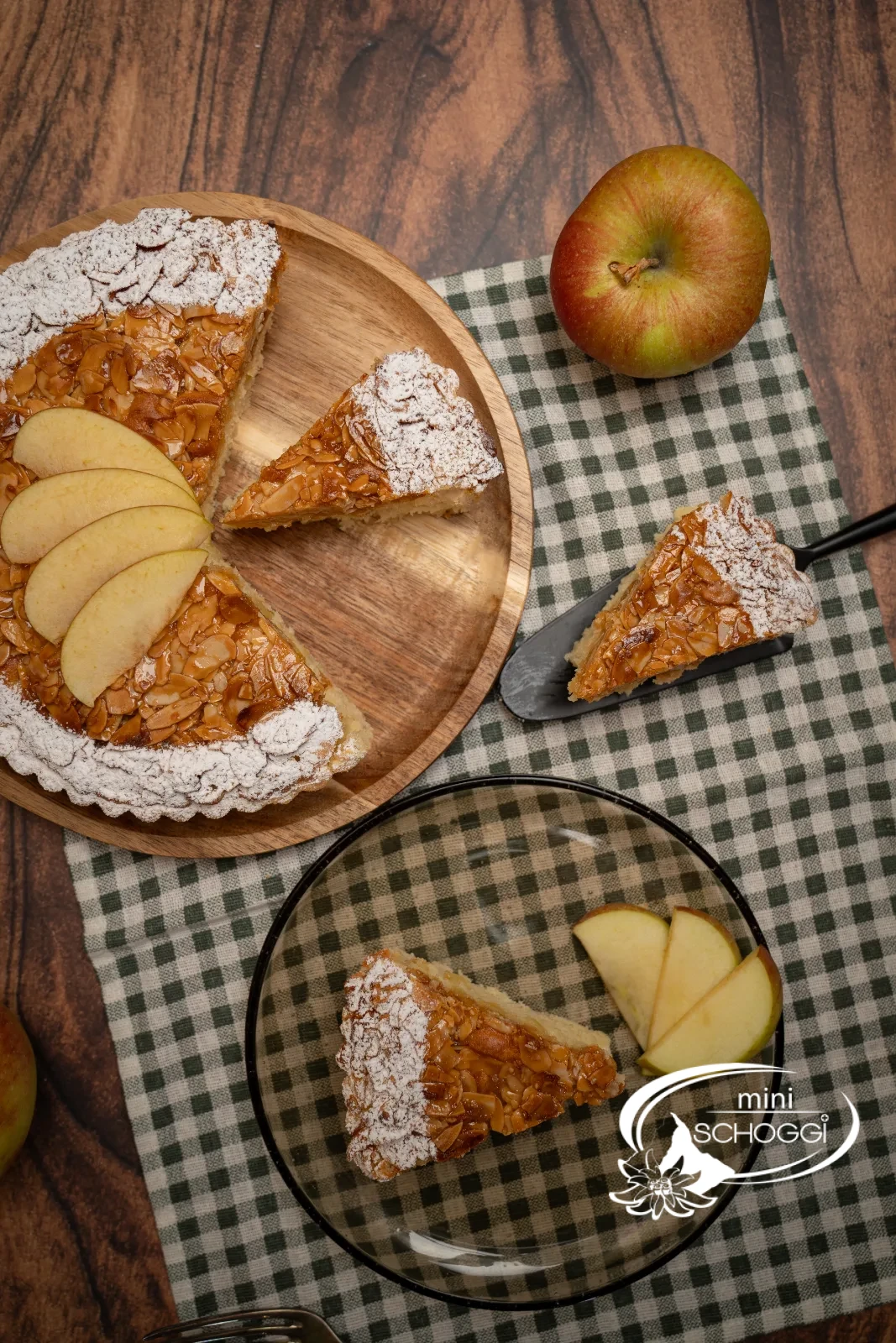 Crostata di mele con copertura dorata di mandorle affettate, il bordo spolverato di zucchero a velo