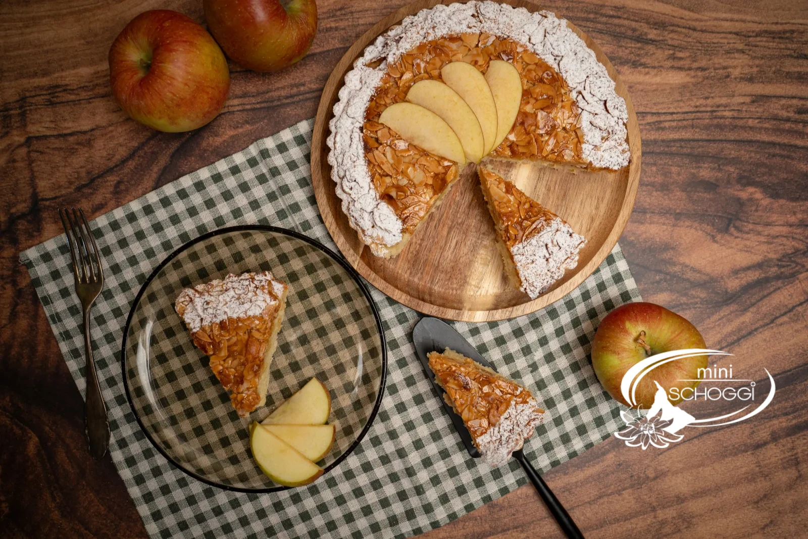 Crostata di mele con copertura dorata di mandorle a lamelle, il bordo spolverato di zucchero a velo