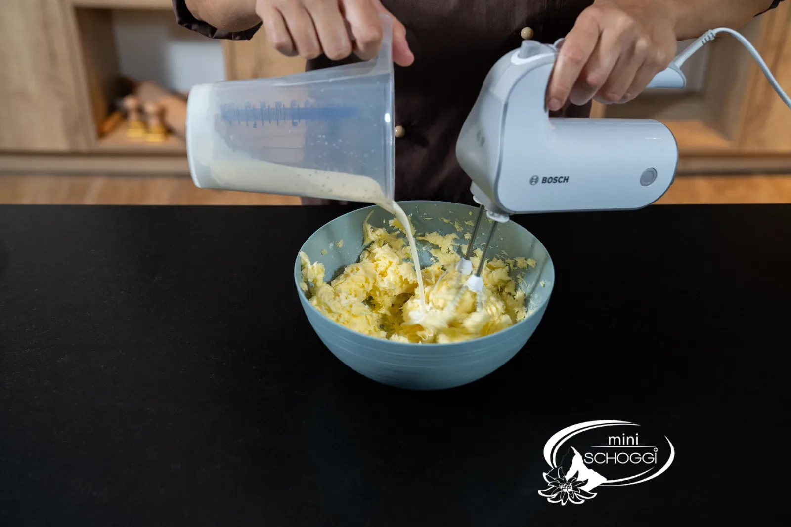 Flüssiger Vollrahm wird zur aufgeschlagenen Butter gegossen