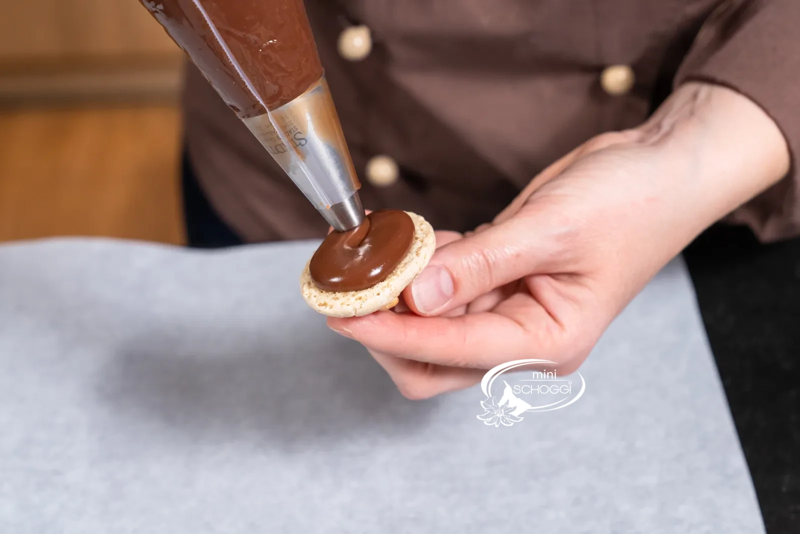 Ein Tupfen Ganache wird auf die Unterseite eines Kekses gespritzt