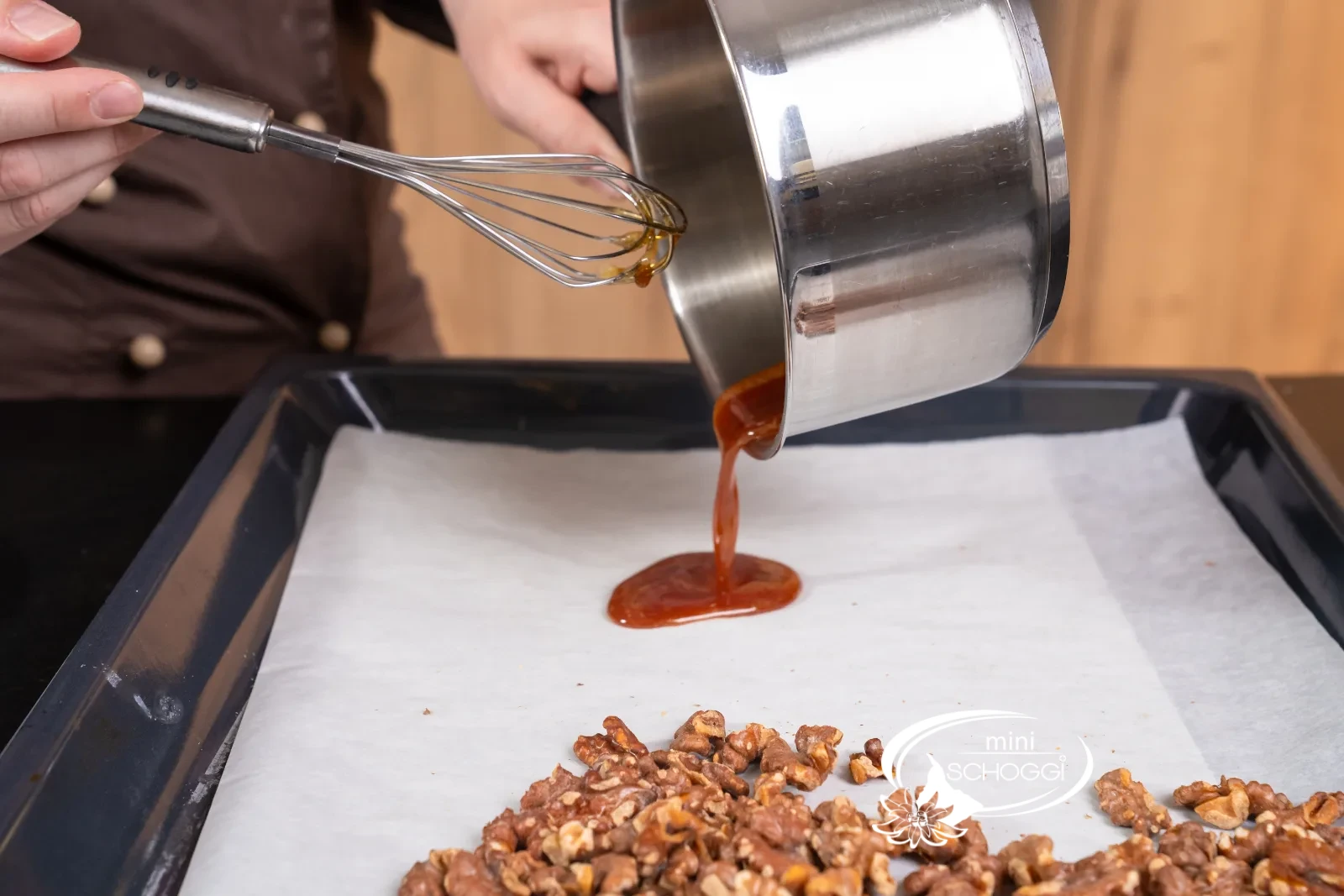Il caramello caldo viene versato sulla carta da forno accanto alle noci tostate