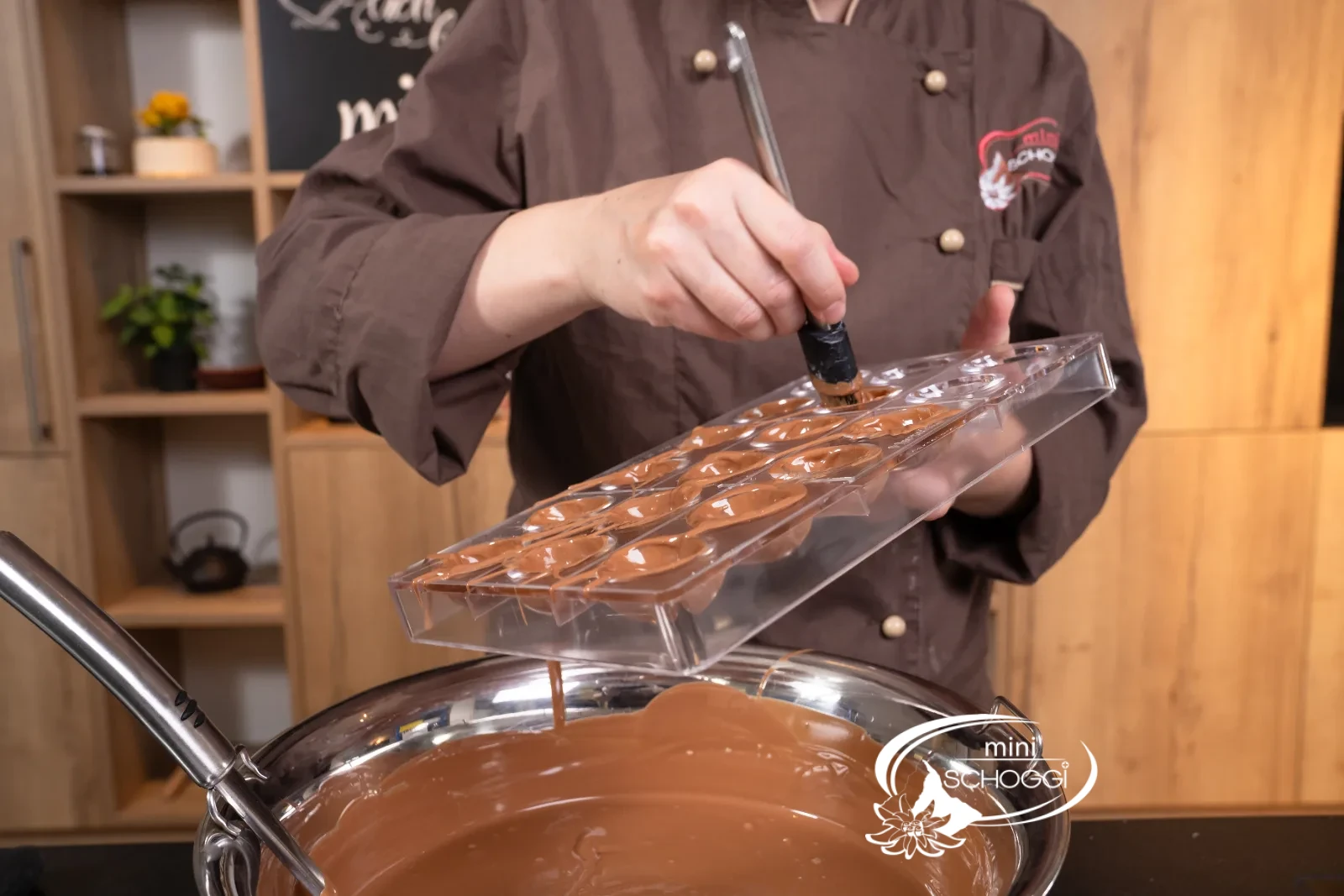 Ogni cavità dello stampo a noce riceve col pennello un sottile strato di cioccolato
