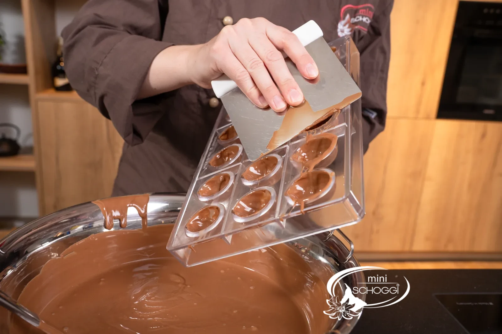 La copertura di cioccolato temperata viene versata nello stampo col mestolo