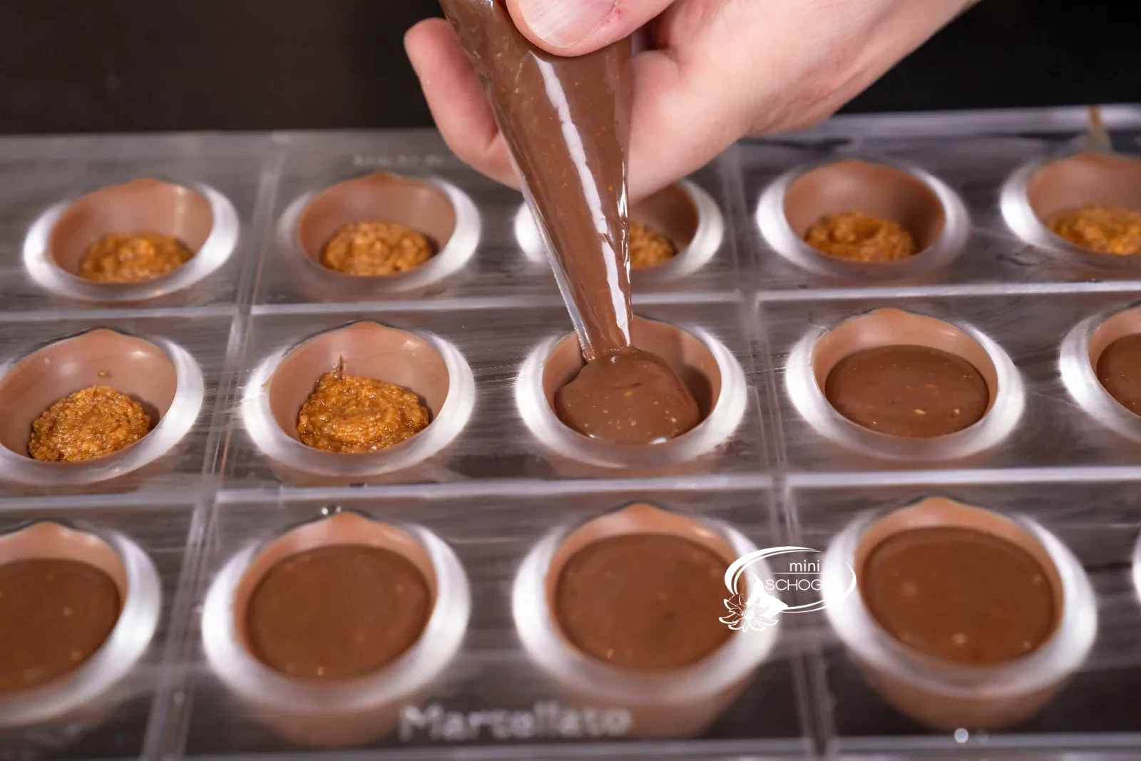 La ganache viene dosata sopra la pasta di noci nelle praline