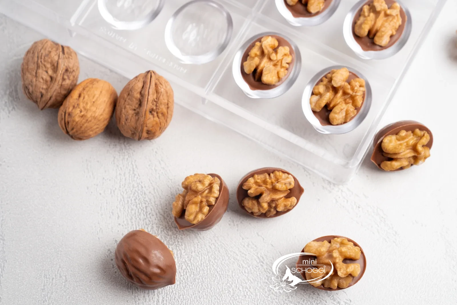 Praline alle noci finite con noci intere accanto allo stampo per praline