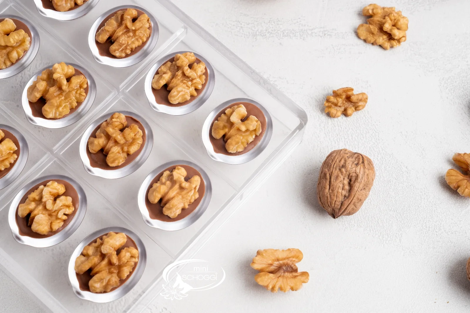 Praline alle noci finite con noci intere accanto allo stampo per praline