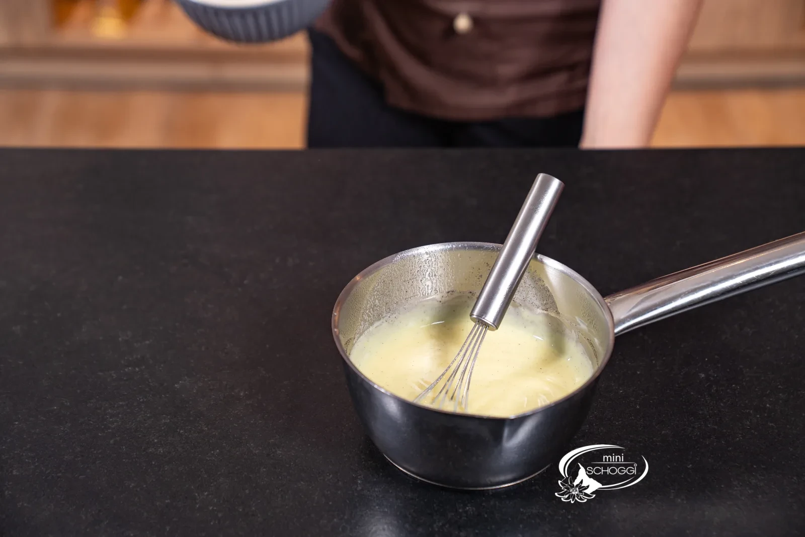Eingedickte Vanillecreme im Topf mit dem Schwingbesen