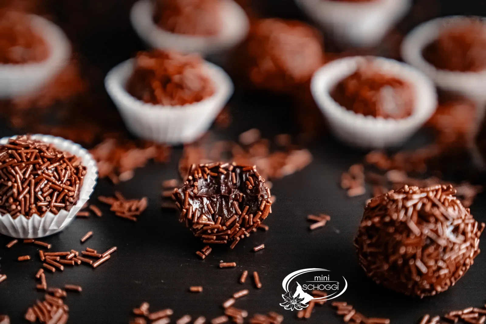 Brigadeiros roulés dans des vermicelles de chocolat, présentés dans des capsules de chocolat blanches