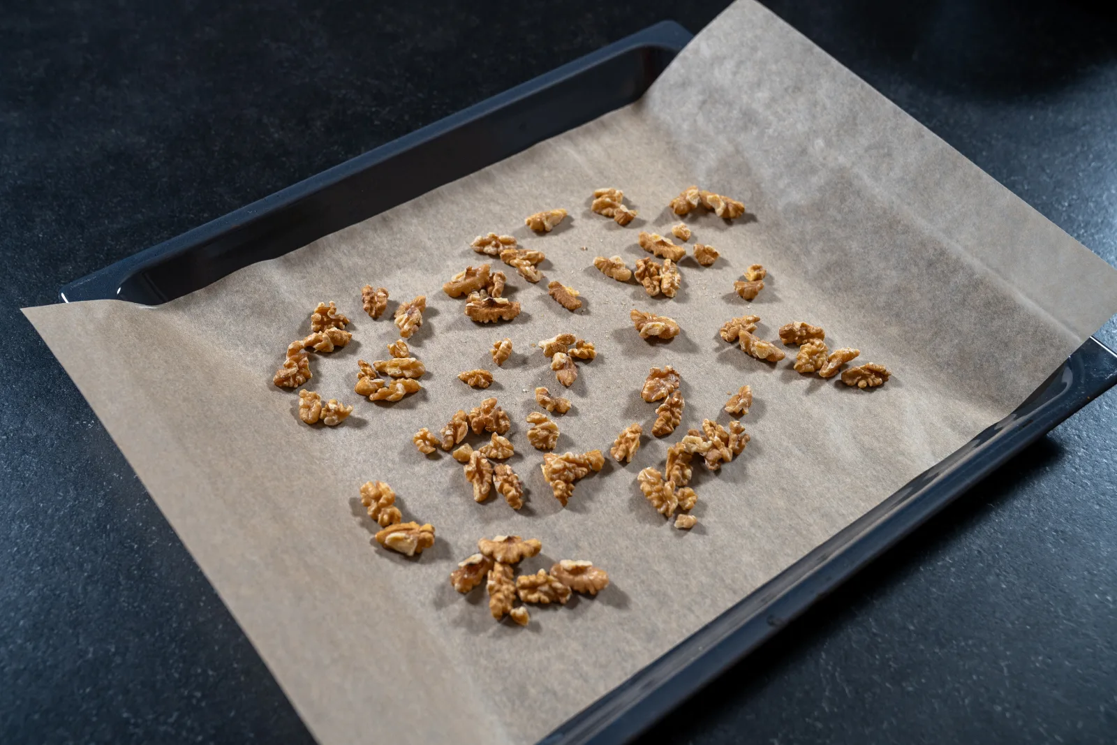 Walnut kernels on a baking tray with baking paper for roasting