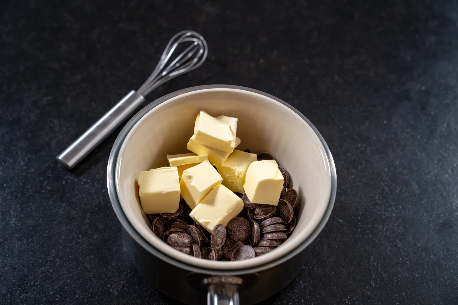 Cubes of butter and dark chocolate drops in the pan over the water bath