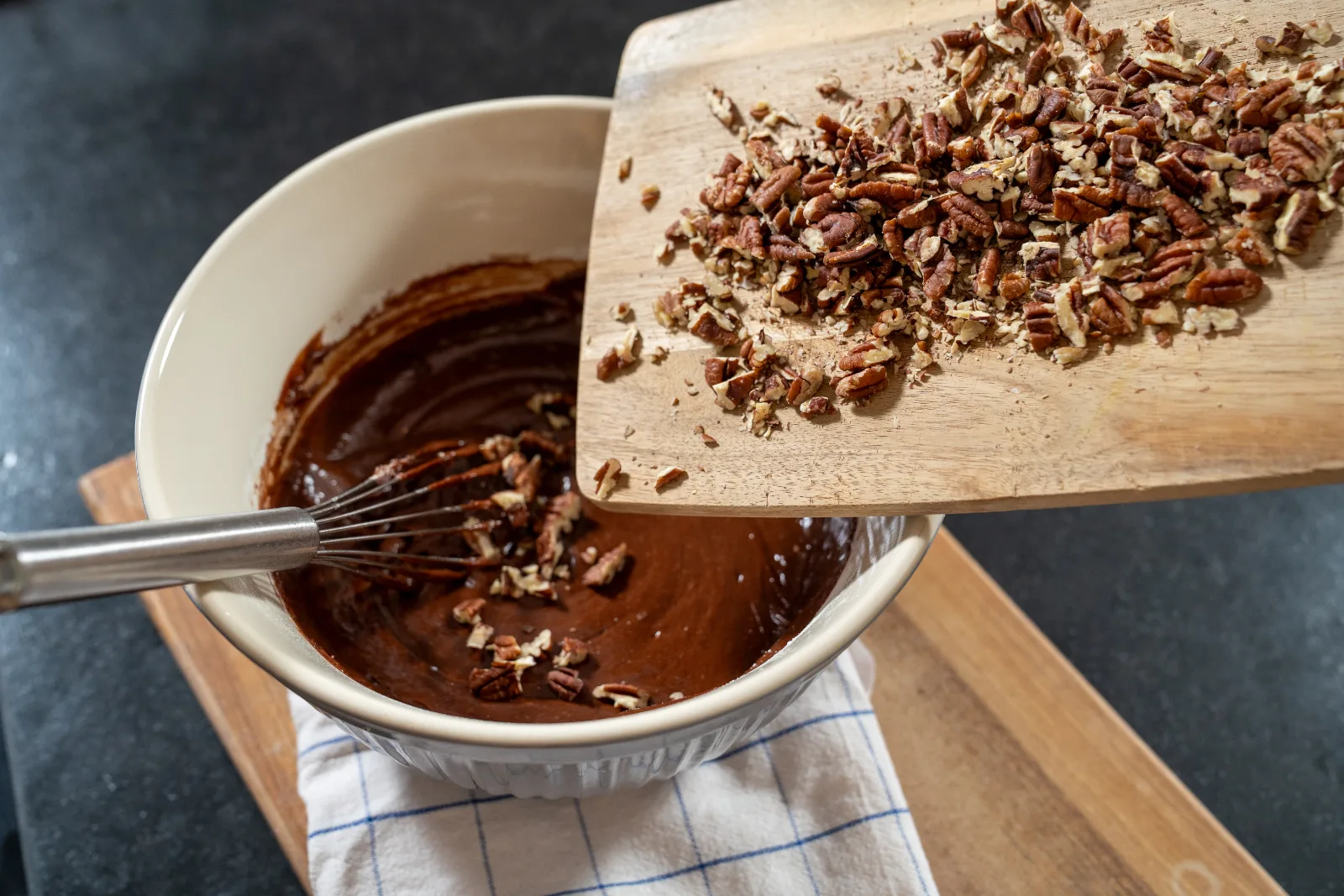 Chopped pecans being added to the brownie dough