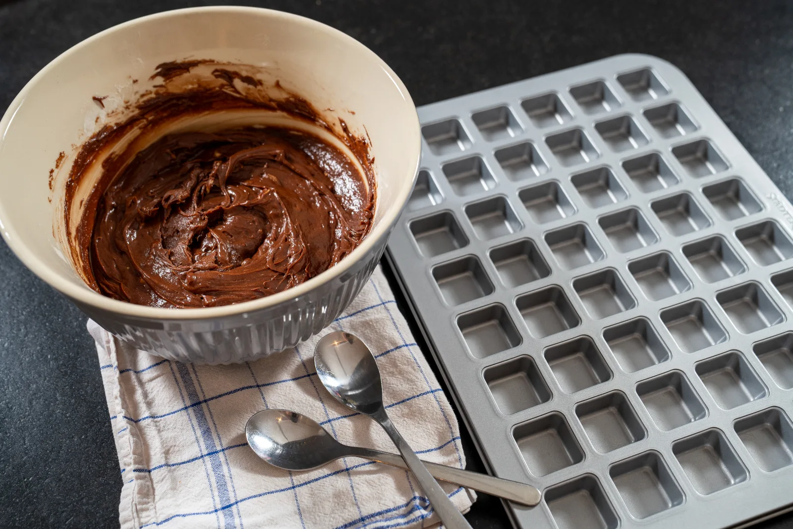 Finished brownie dough next to the empty mini baking tin