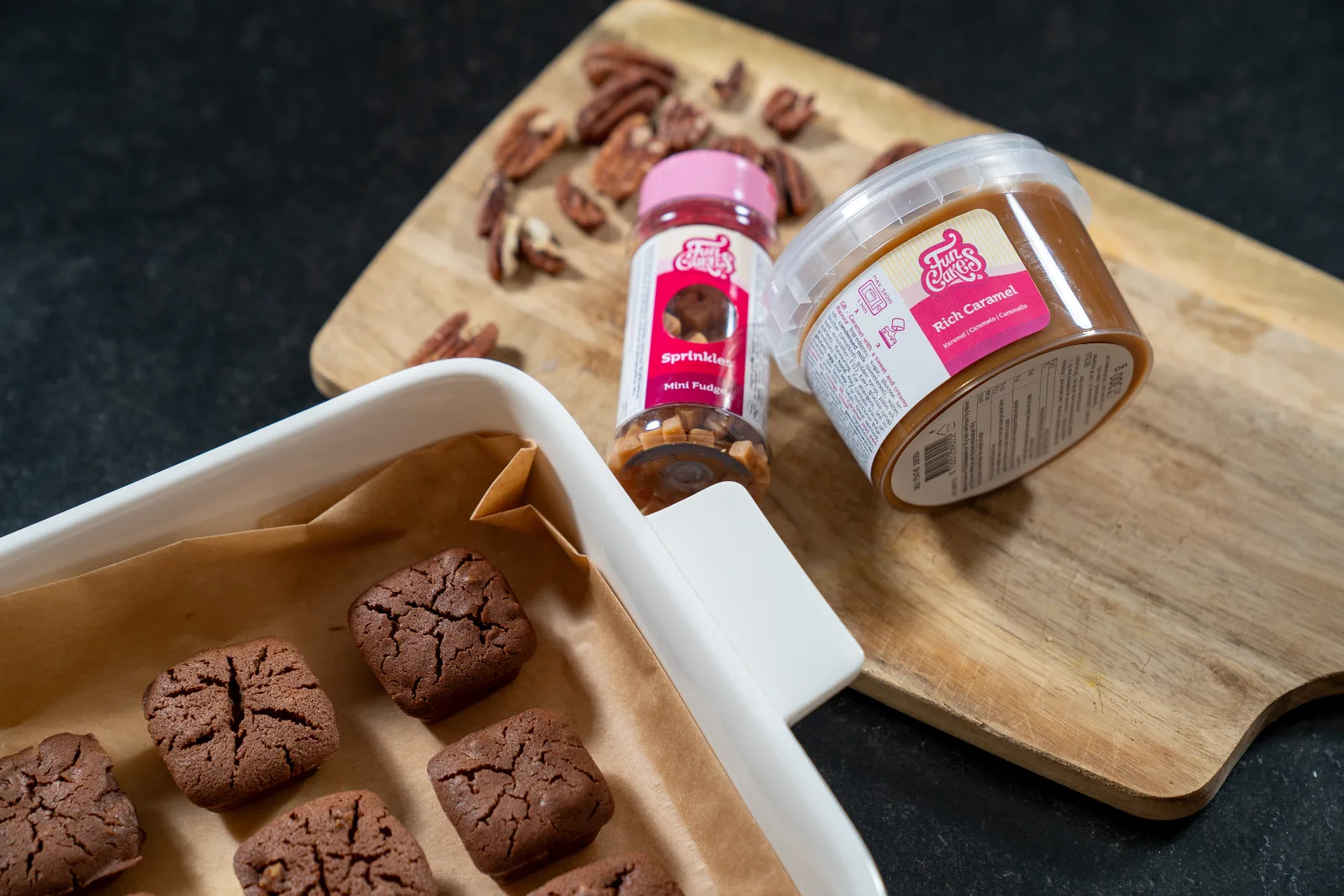Baked brownies next to caramel cream and caramel chips for decorating