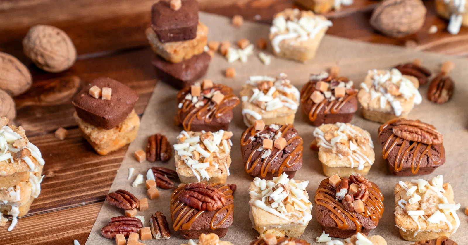 Finished blondies and brownies in rows on baking paper, decorated with pecans and caramel