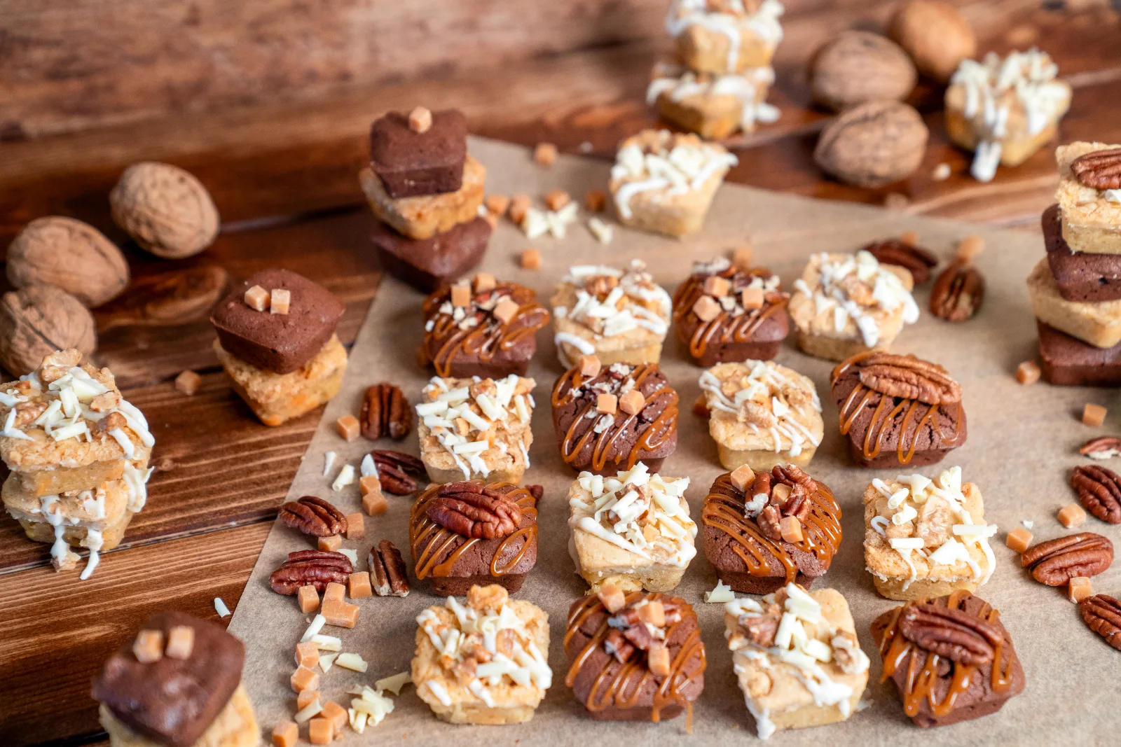 Finished blondies and brownies in rows on baking paper, decorated with pecans and caramel