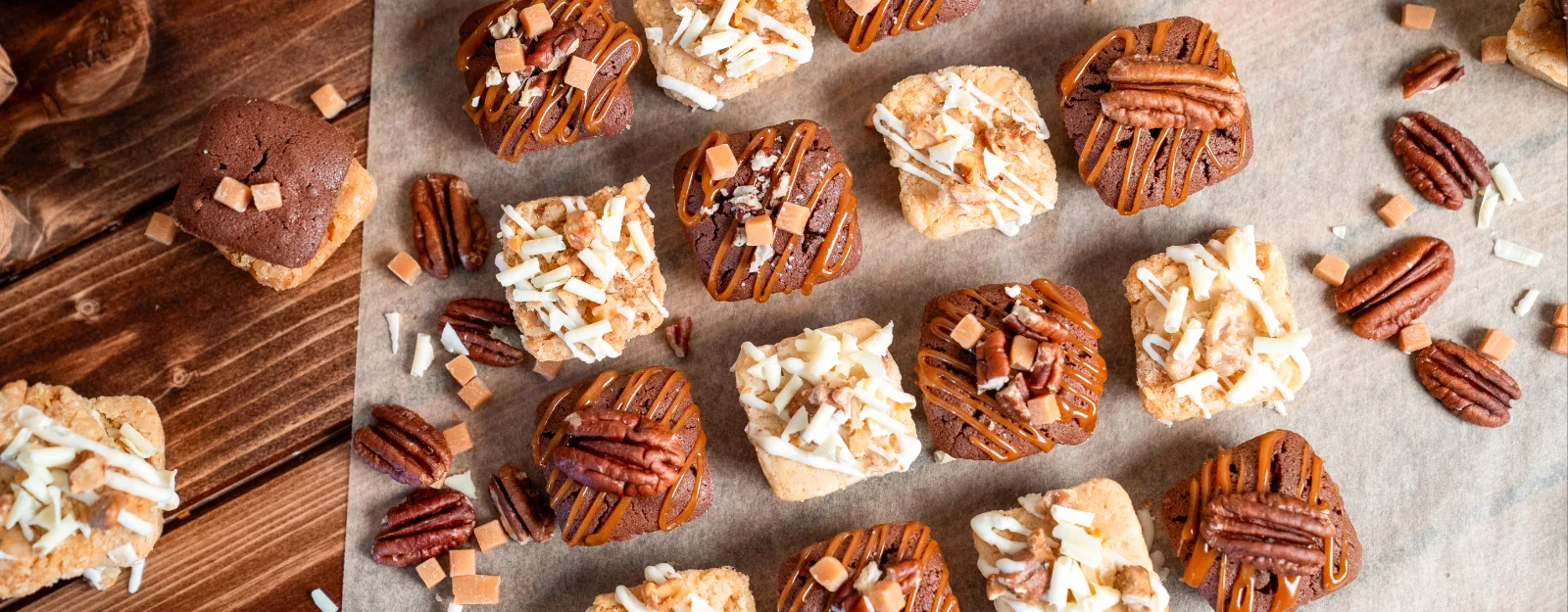 Finished blondies and brownies in rows on baking paper, decorated with pecans and caramel