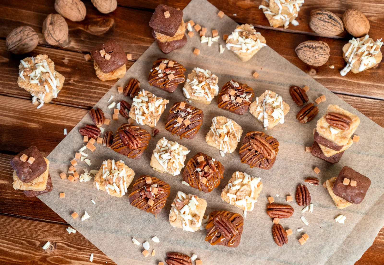Finished blondies and brownies in rows on baking paper, decorated with pecans and caramel