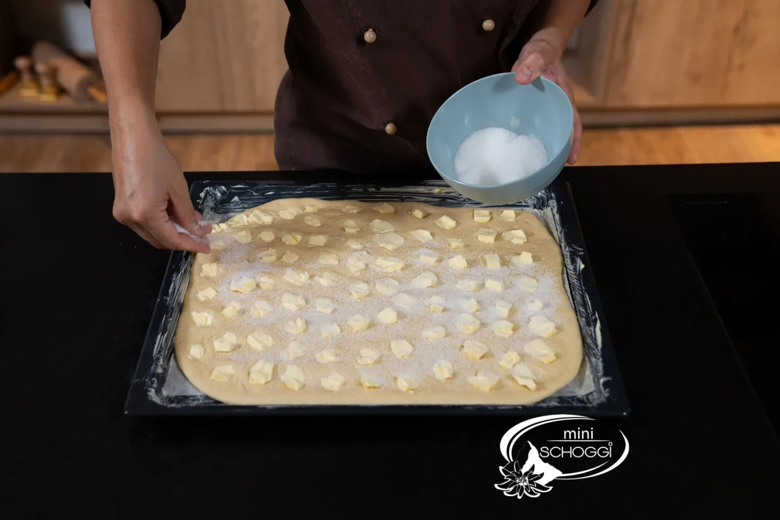 Zucker wird über den mit Butter belegten Hefeteig gestreut