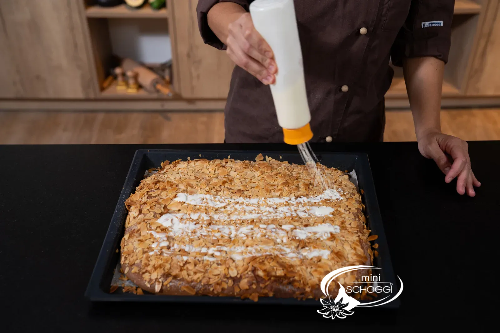 Rahm wird aus einer Flasche über den heissen Butterkuchen gegossen