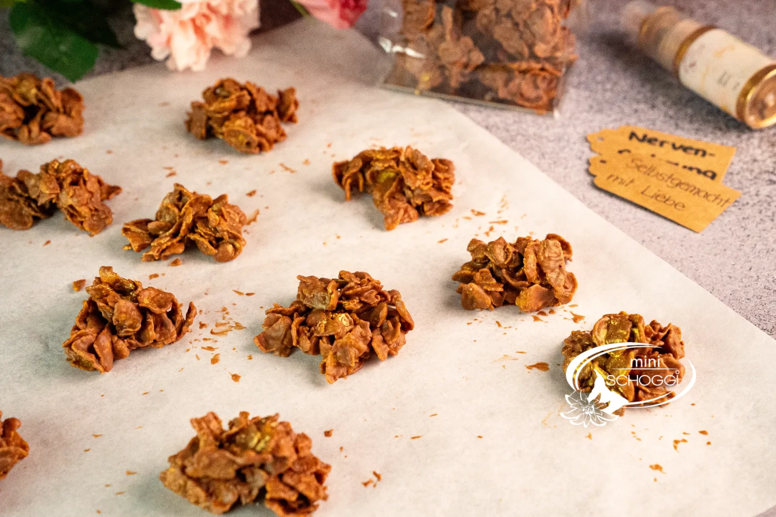 Biscotti cornflakes nel sacchetto trasparente con fiocco, accanto singoli croccantini al cioccolato