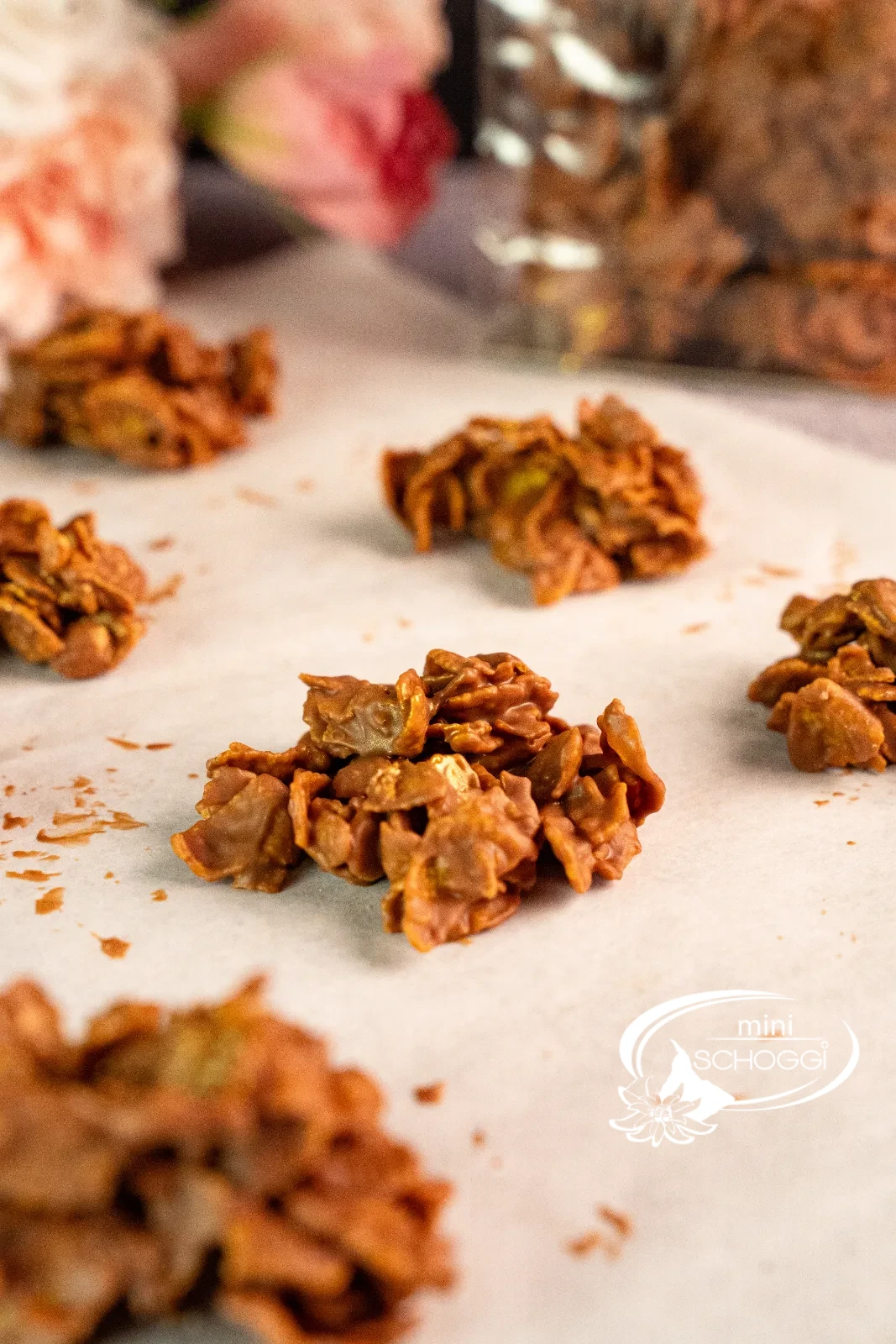 Biscotti cornflakes nel sacchetto trasparente con fiocco, accanto singoli croccantini al cioccolato