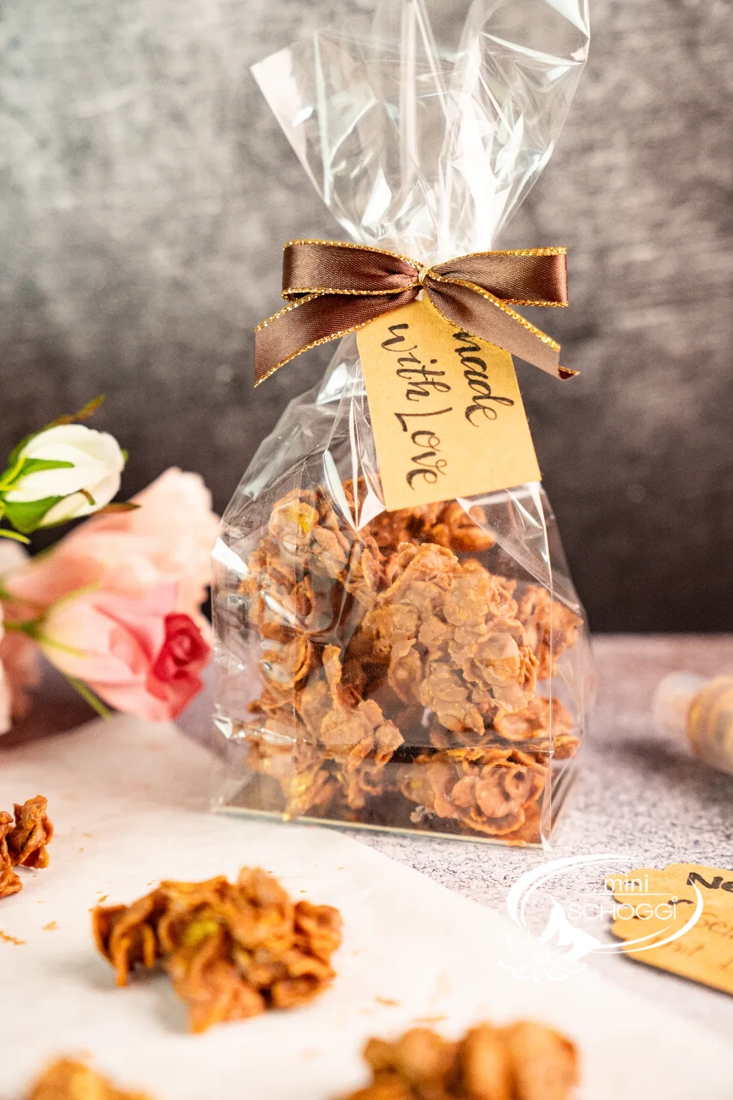 Biscotti cornflakes nel sacchetto trasparente con fiocco, accanto singoli croccantini al cioccolato