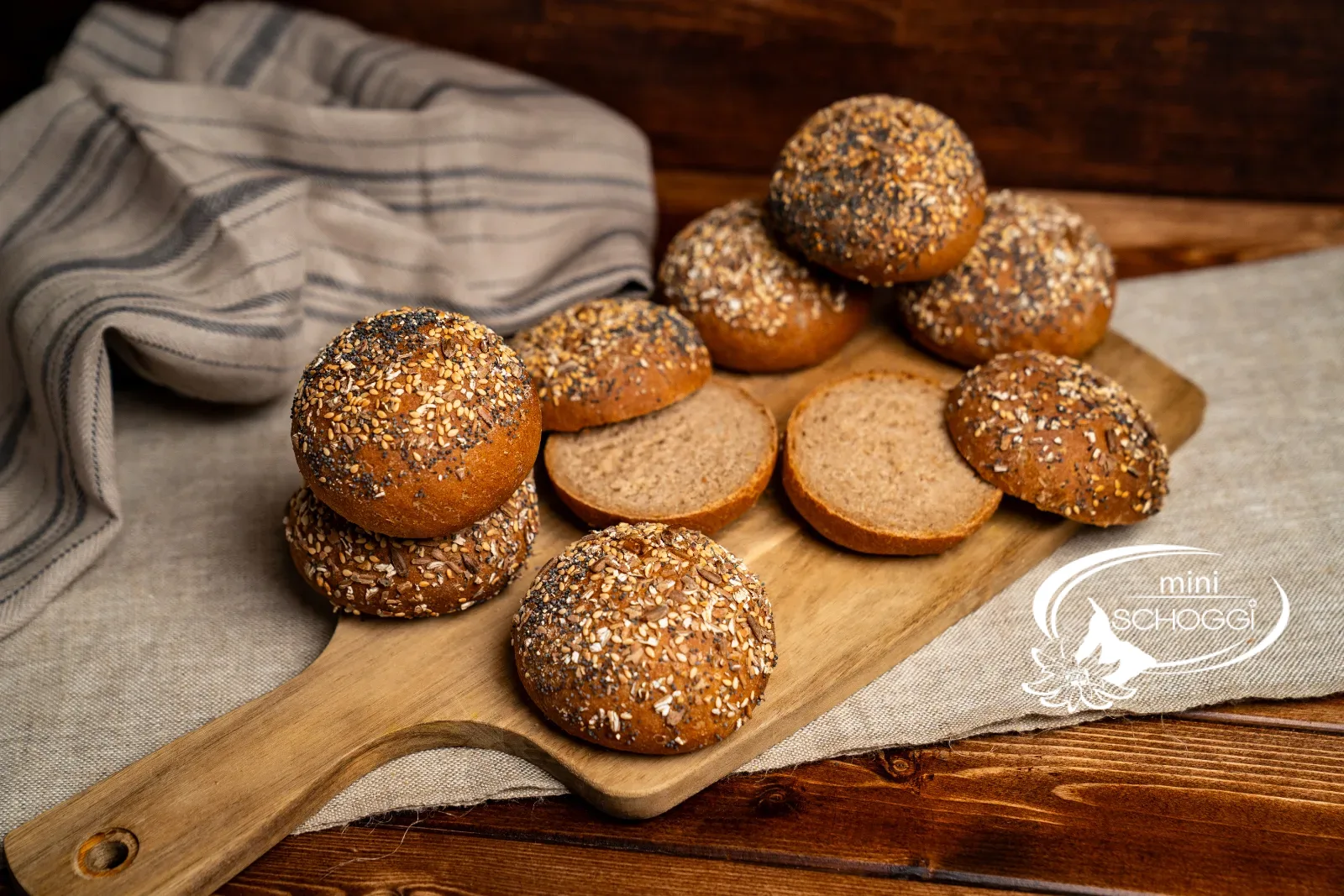 Dinkel-Vollkornbrötchen auf einem Holzbrett mit Leinentuch