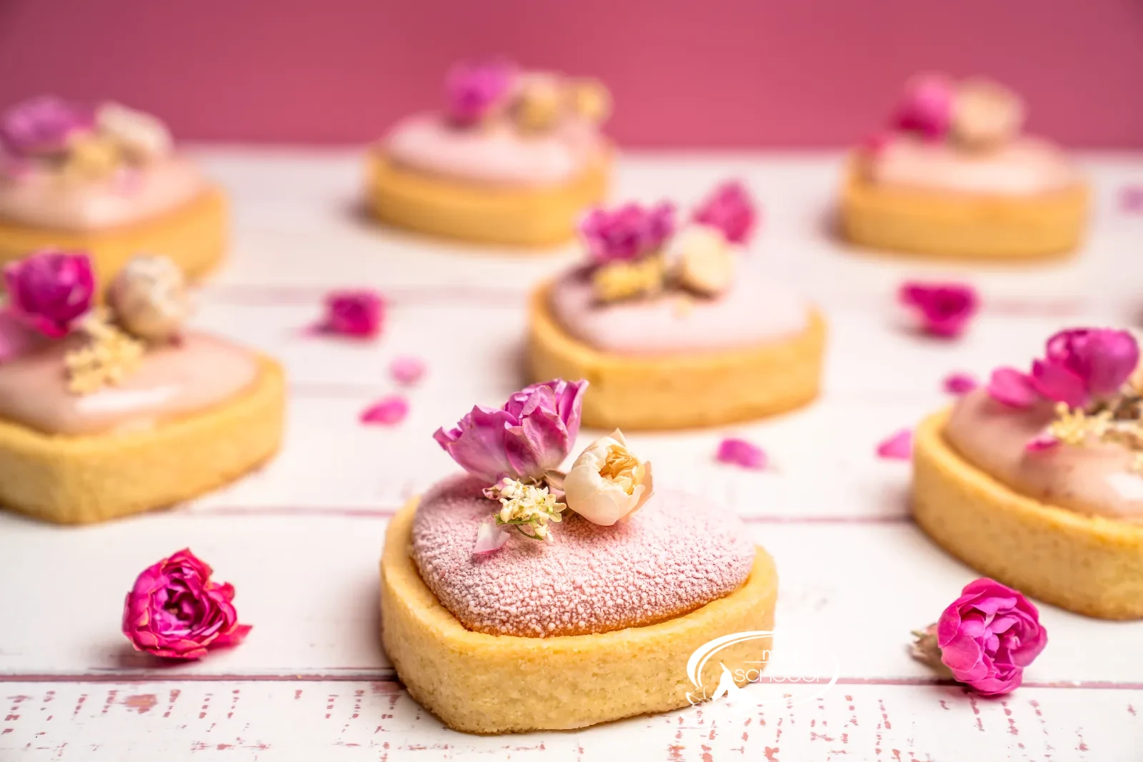 Pasticceria fragola-limone a forma di cuore con glassa rosa e boccioli di rosa commestibili