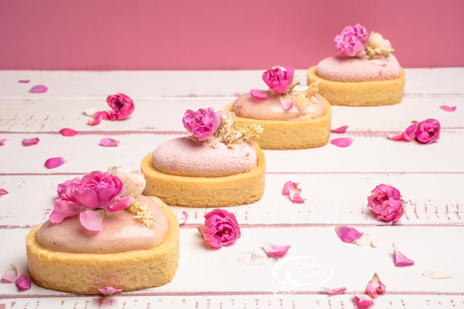 Pasticceria fragola-limone a forma di cuore con glassa rosa e boccioli di rosa commestibili