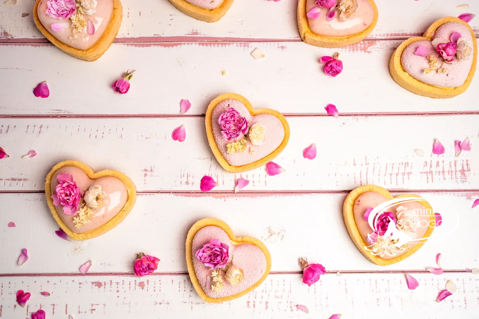 Pasticceria fragola-limone a forma di cuore con glassa rosa e boccioli di rosa commestibili