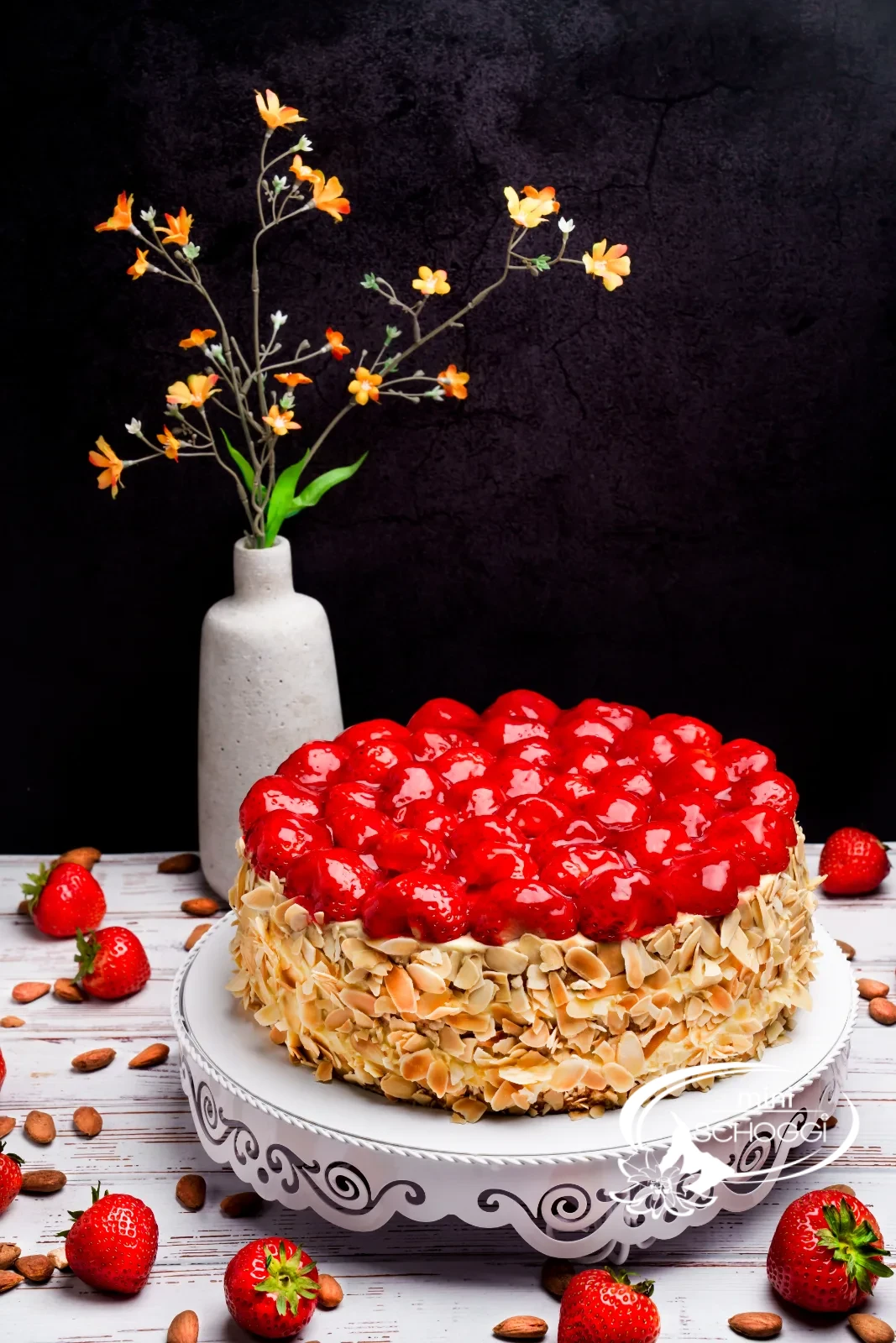 Torta di fragole tagliata con bordo di mandorle e fragole lucide