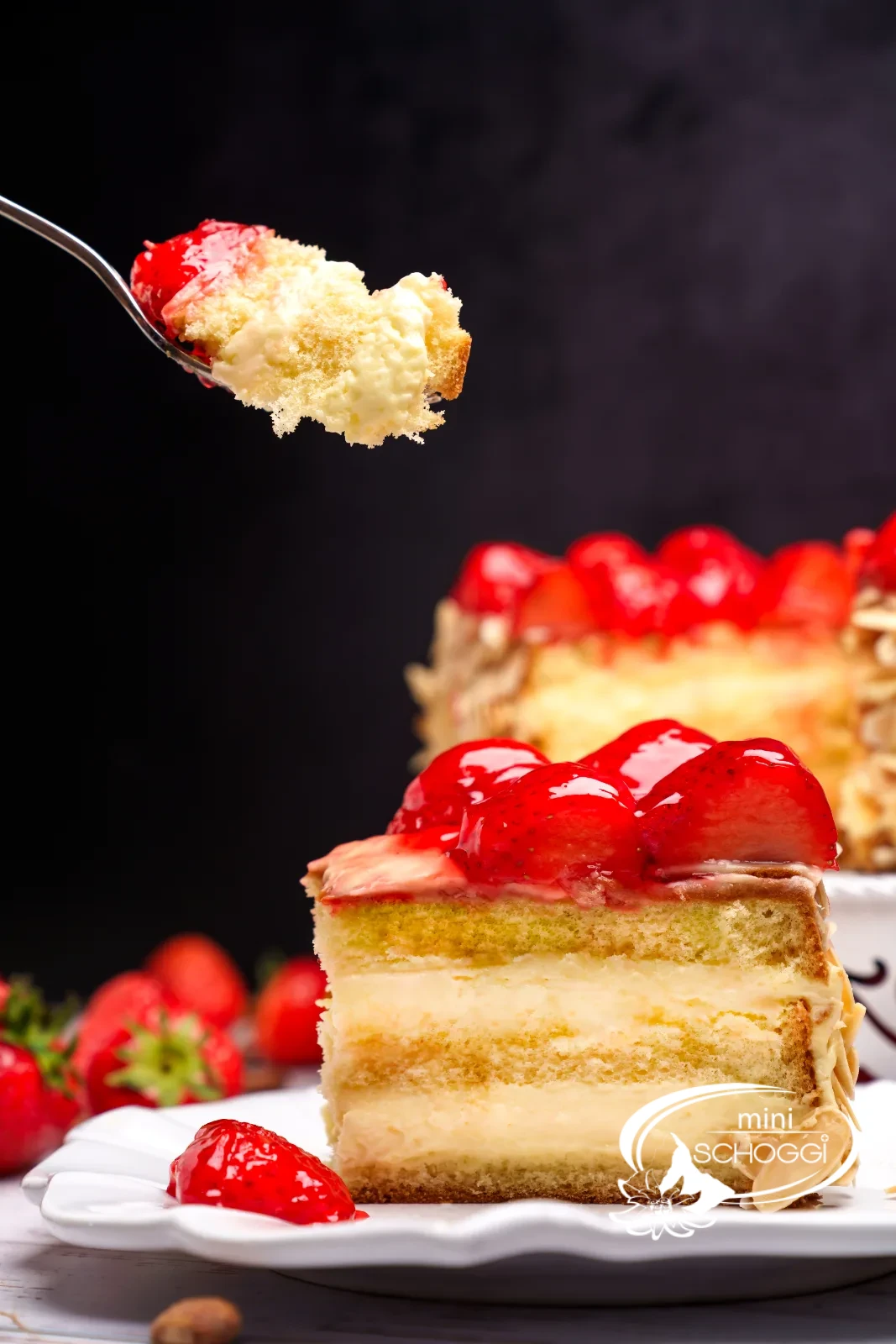 Torta di fragole tagliata con bordo di mandorle e fragole lucide