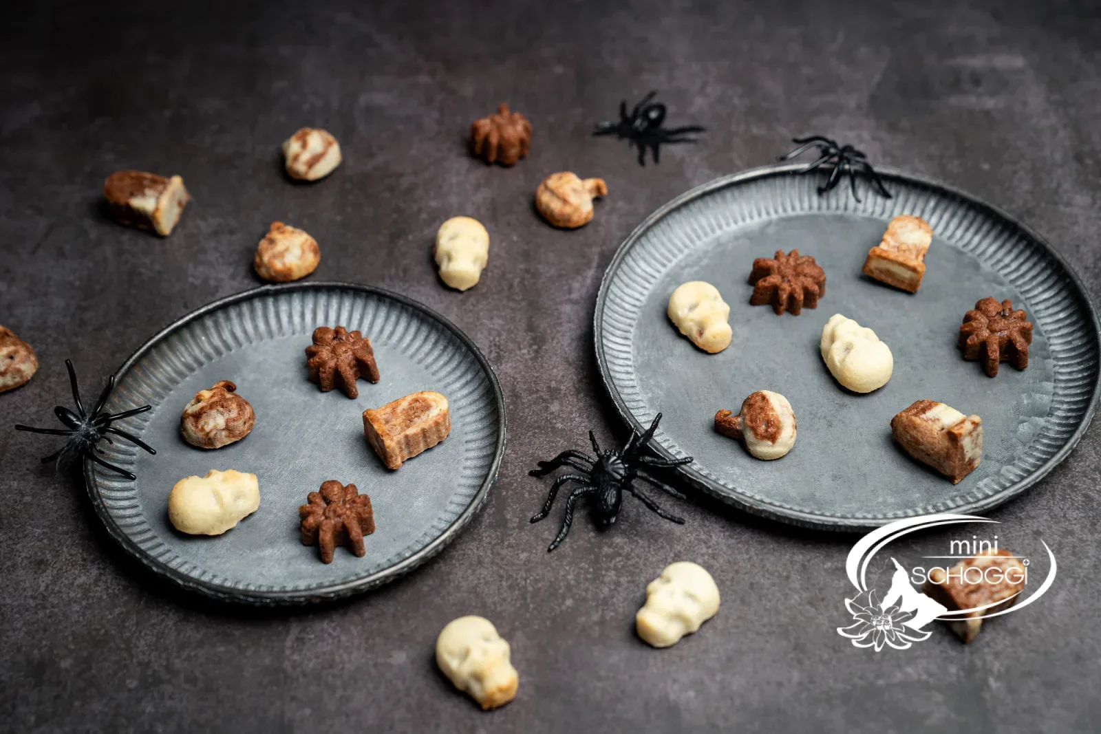 Gefüllte Halloween-Guetzli in Form von Spinnen, Totenköpfen und Grabsteinen auf Metalltellern