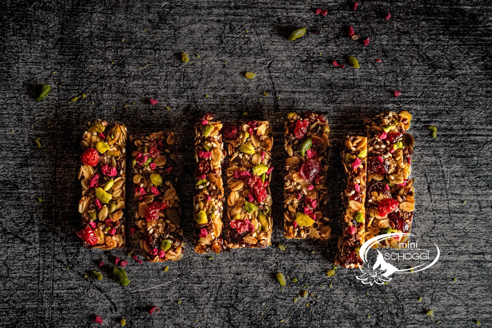 Dodici croccanti barrette ai cereali con pistacchi, mirtilli rossi e lamponi una accanto all'altra