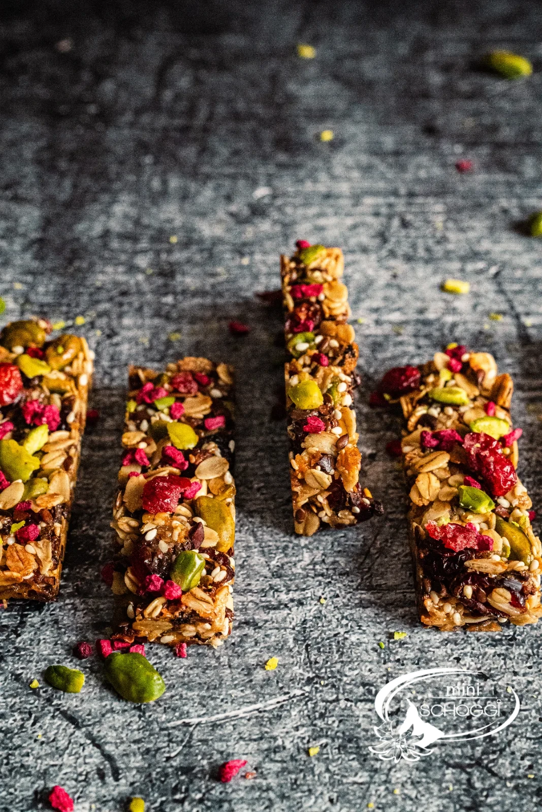 Dodici croccanti barrette ai cereali con pistacchi, mirtilli rossi e lamponi una accanto all'altra