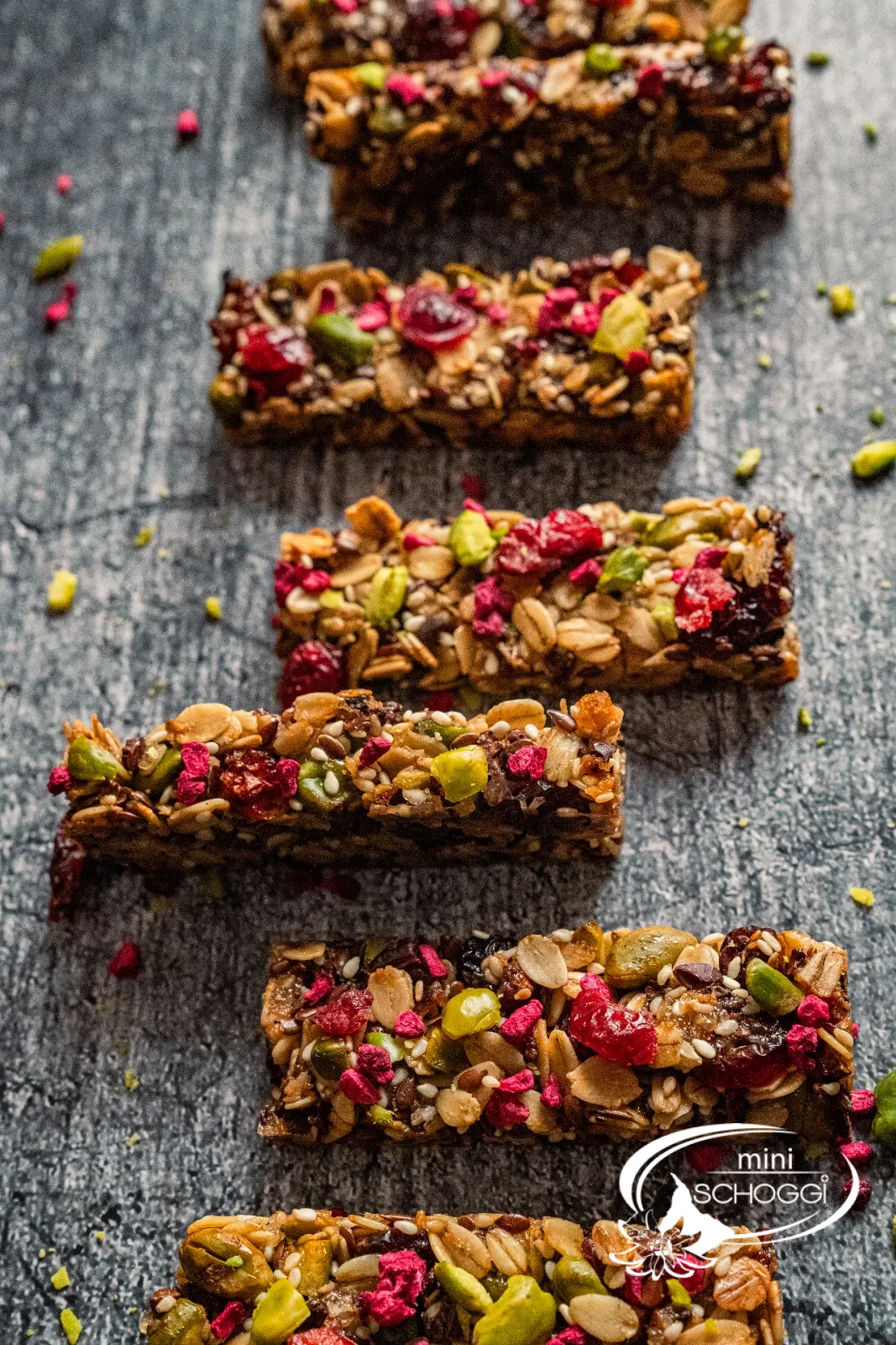Dodici croccanti barrette ai cereali con pistacchi, mirtilli rossi e lamponi una accanto all'altra