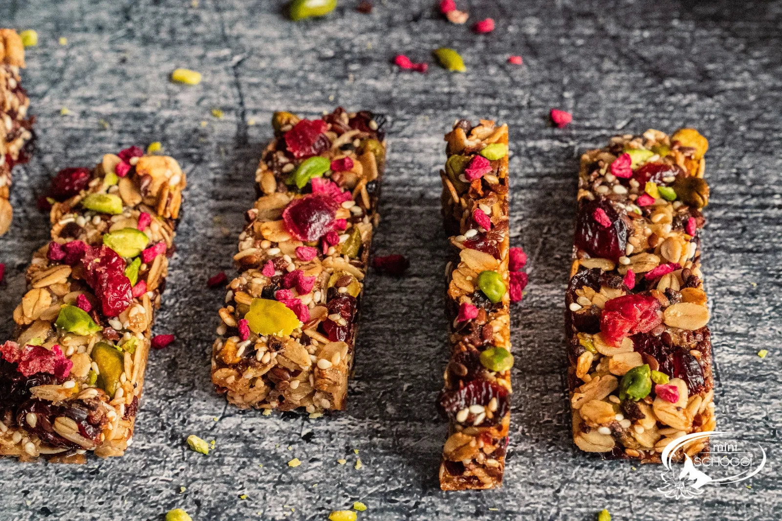 Dodici croccanti barrette ai cereali con pistacchi, mirtilli rossi e lamponi una accanto all'altra