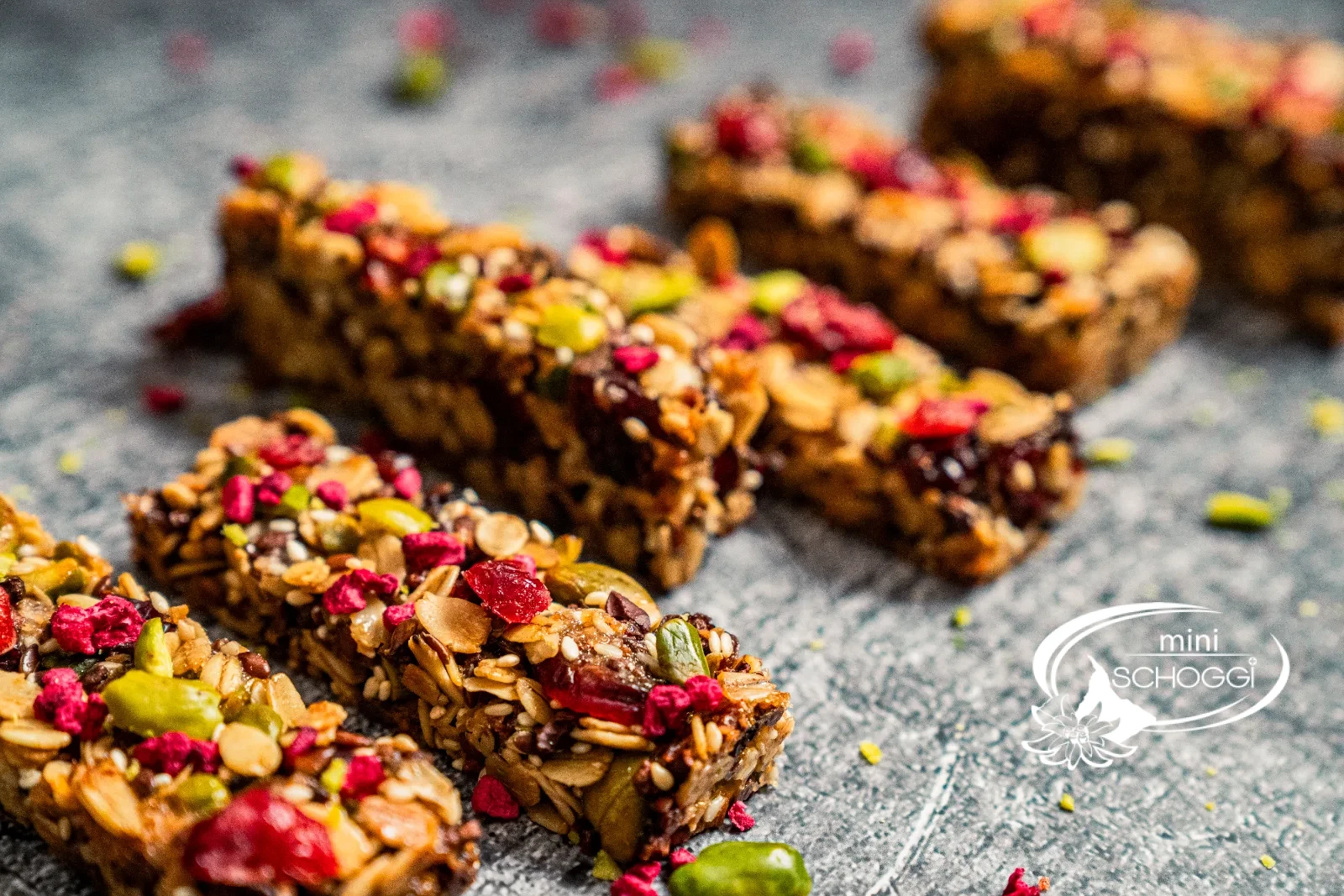 Dodici croccanti barrette ai cereali con pistacchi, mirtilli rossi e lamponi una accanto all'altra