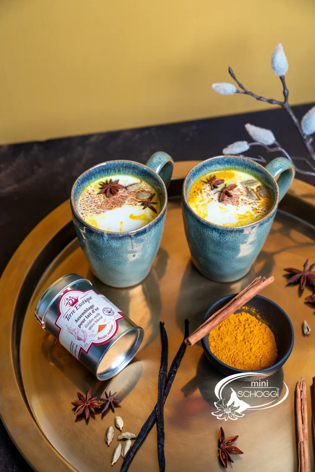 Golden Milk in zwei Keramiktassen mit Kurkuma, Zimtstangen und Vanille