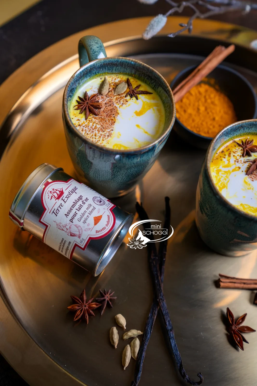 Golden Milk in zwei Keramiktassen mit Kurkuma, Zimtstangen und Vanille