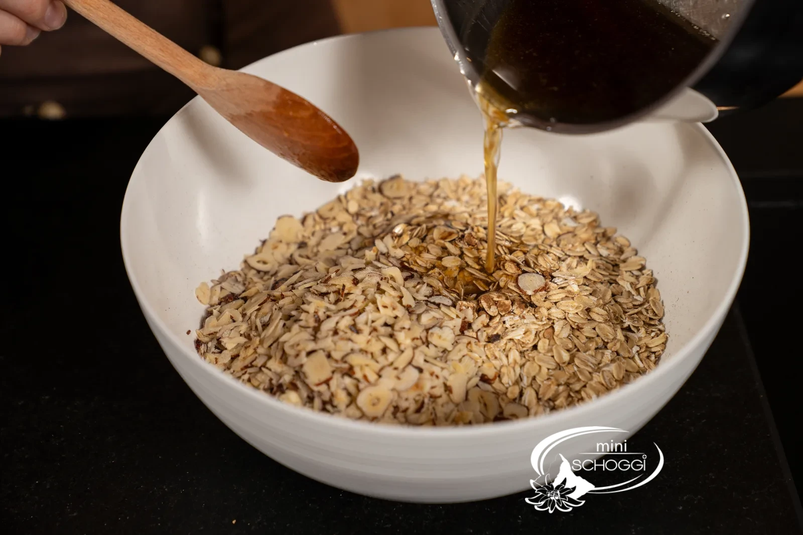 Il composto di miele caldo viene versato sui fiocchi d'avena con le nocciole