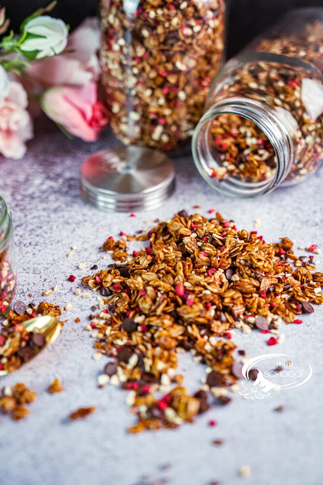 Granola fatta in casa con lamponi e cioccolato, accanto due vasetti di scorta