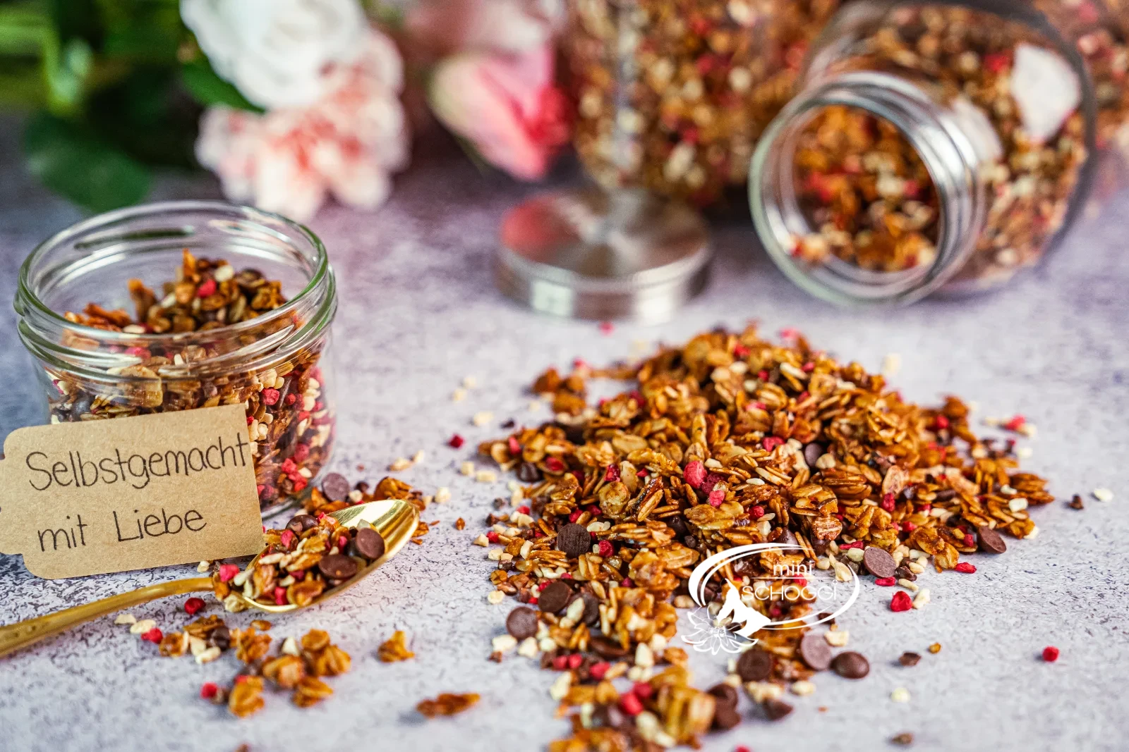Granola fatta in casa con lamponi e cioccolato, accanto due vasetti di scorta