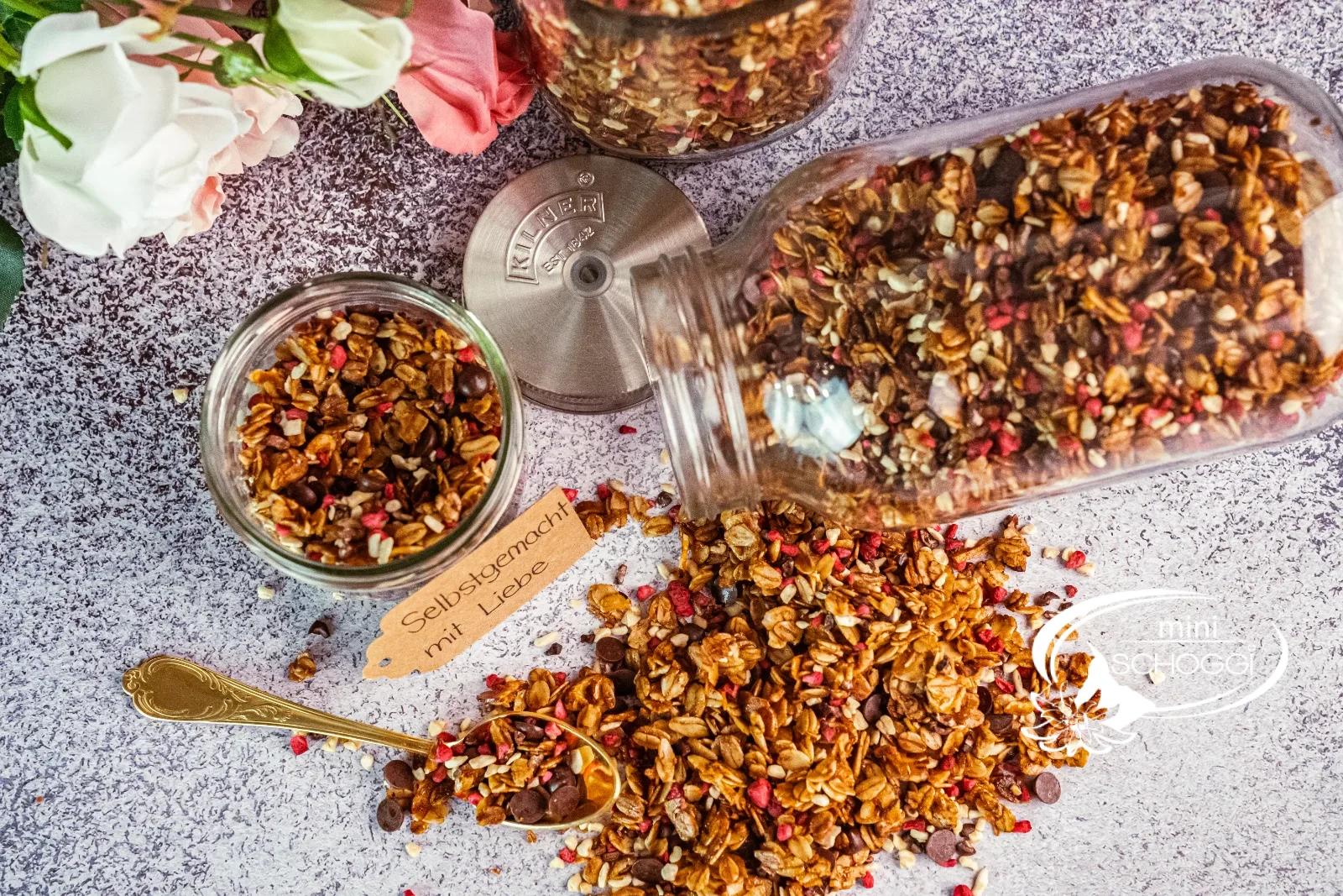 Granola fatta in casa con lamponi e cioccolato, accanto due vasetti di scorta