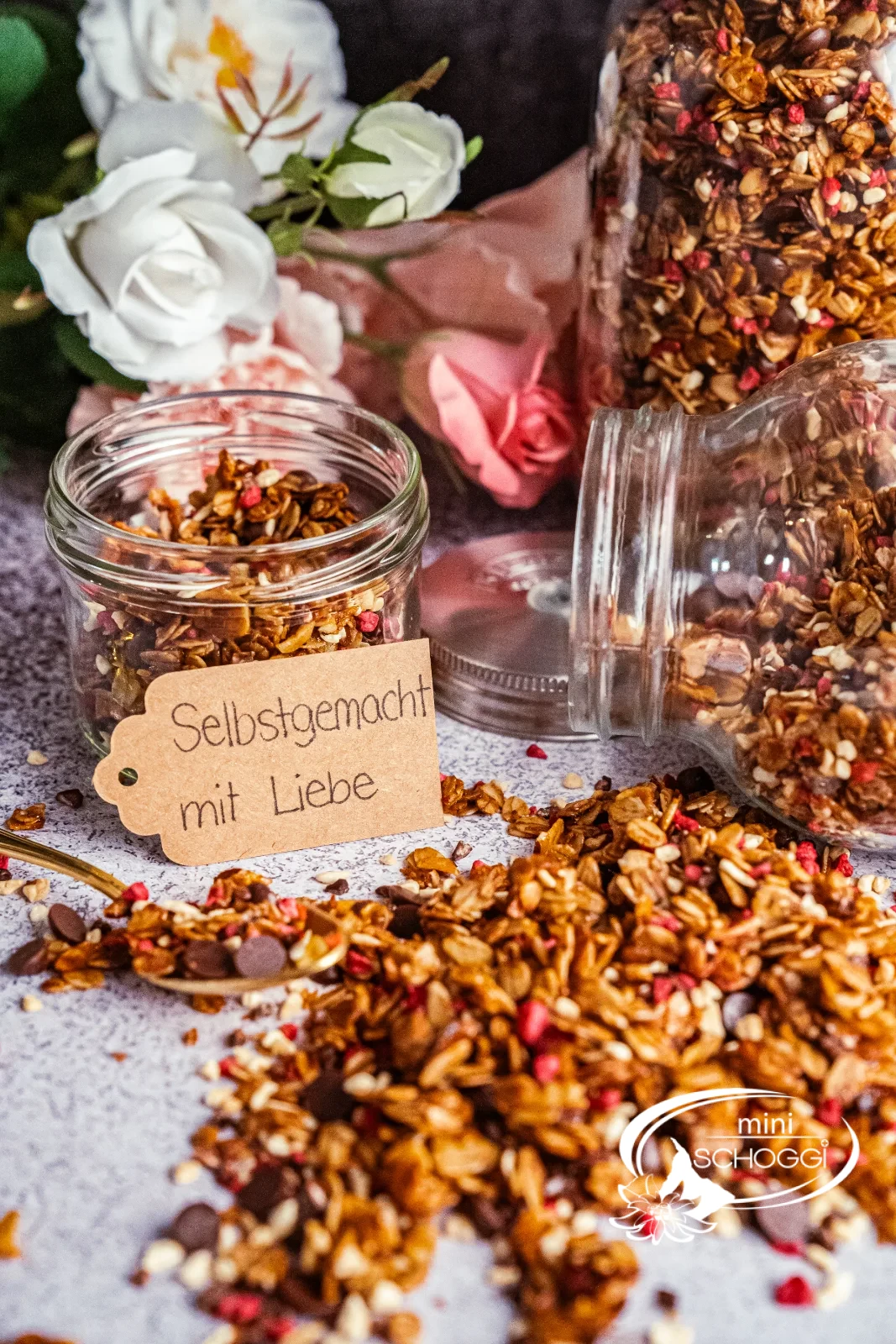 Granola fatta in casa con lamponi e cioccolato, accanto due vasetti di scorta